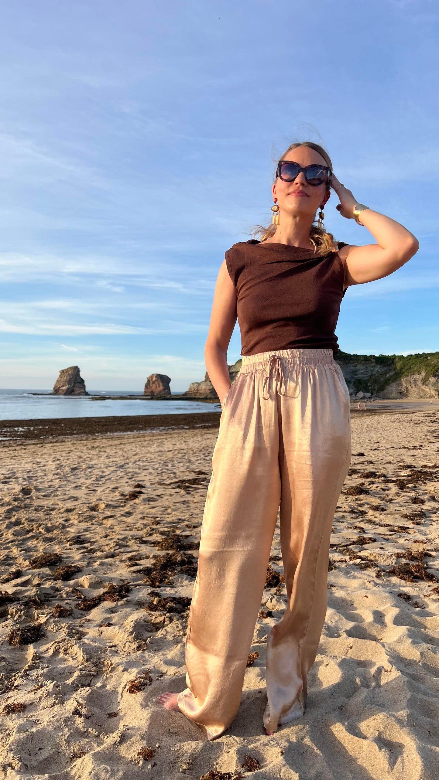 Pantalon satiné doré Oro à taille élastiquée et cordon, couple ample et fluide, porté en bord de mer - HAVANA PARIS